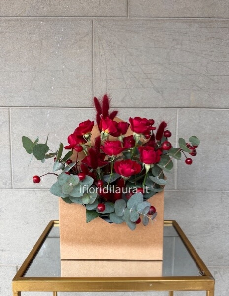 Elegante composizione a forma di lettera con rose rosse e verde decorative.